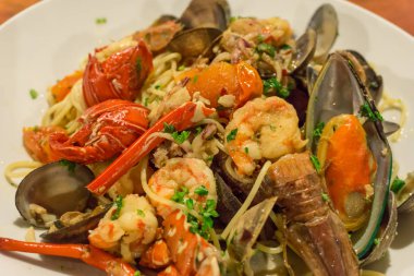 Deniz ürünleri makarna makarna midye, karides, deniz ürünleri kokteyl ile küme üzerinde ahşap masa salata var