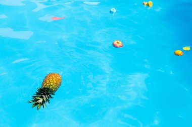 Havuzda yüzen farklı meyve ve oyuncaklar.