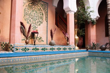 Renkli kiremitleri ve verandasının yanında altın bir tencere ve Fas 'ta bitkileri olan küçük bir havuzu olan bir avlu.