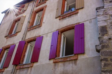 Renkli ahşap pencereli eski bir binanın ön cephesinden gün ışığı geliyor.