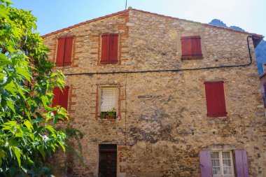 Güneşli bir günde renkli pencere çerçeveli taştan bir evin ön cephesi