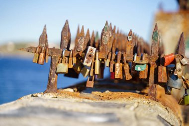 Güneşli bir günde, deniz kenarındaki korkuluklarda paslı kilitler.