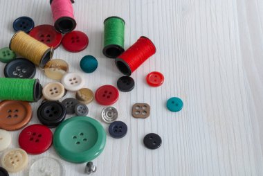 Beyaz ahşap arka planda iplik ve düğmeler makaraları genel üst görünümü