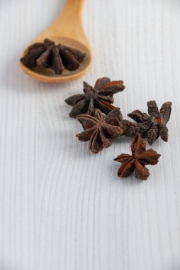 Kopya alanı ile beyaz ahşap arka planda yıldızlı Anis ile ahşap kaşık dikey yakın çekim