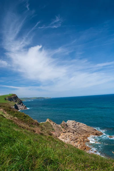スペイン北部 カンタブリア州の青い海と白い雲を持つ岩の海岸の日当たりの良い垂直風景 — ストック写真