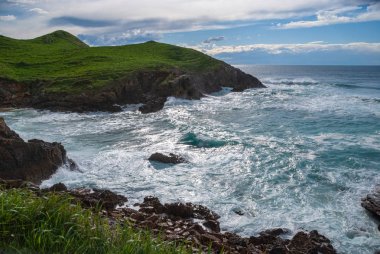 Cantabria, İspanya, Avrupa'da öğleden sonra dalgalı deniz ile yeşil sahil Manzara