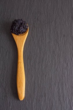 Kopya alanı ile dikey kayrak arka plan üzerinde tahta bir kaşık havyar üst görünümü