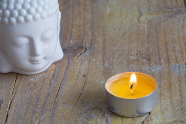 Kopya alanı ile yatay olarak yıpranmış ahşap tahta üzerinde beyaz buda figürü ve mum üst görünümü