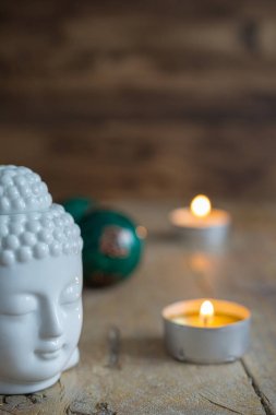 Beyaz buda figürü, Çin topları ve yıpranmış ahşap masa ve dikey koyu arka plan üzerinde iki mum üst görünümü