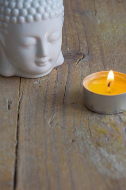 Kopya alanı ile yıpranmış ahşap tahta üzerinde beyaz buda figürü ve mum üst görünümü