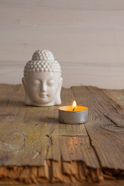 Beyaz buda figürü ve yıpranmış ahşap tahta üzerinde mum