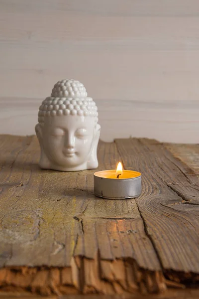 Beyaz buda figürü ve yıpranmış ahşap tahta üzerinde mum