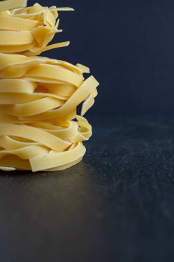 Kopya alanı ile siyah arka plan üzerinde dikey olarak yığılmış fettuccine makarna yakın çekim