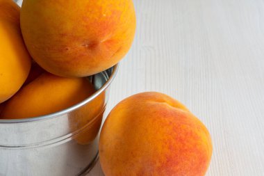 Kopya alanı ile yatay beyaz ahşap arka plan üzerinde yakın çekim metal kase birkaç şeftali üst görünümü