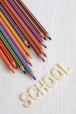 Dikey beyaz ahşap arka planda, kelime Okulu ile birkaç diyagonal renkli kalemler üst görünümü