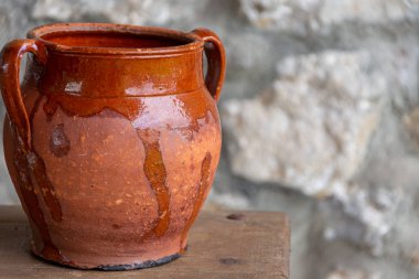 Yatay olarak odak dışında taş arka plan ile ahşap masa üzerinde kil pot yakın çekim