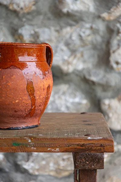 Dikey odak dışında taş arka plan üzerinde yıpranmış ahşap masa üzerinde kil pot yakın çekim