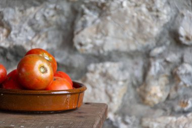 Ahşap masa ve yatay odaklanmamış taş arka plan üzerinde kil kase meyve bahçesi domates üst görünümü