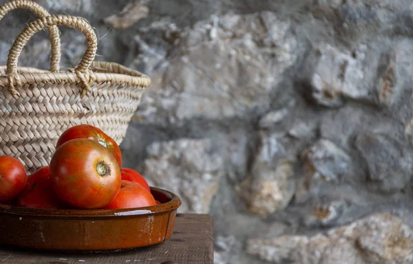 Ahşap masa, sepet ve yatay odaklanmamış taş arka plan üzerinde kil kase meyve bahçesi domates üst görünümü