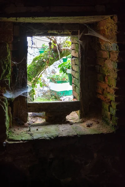 Exterior view from an abandoned dark block window with spider webs vertically