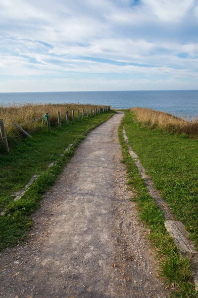 Lonely green road to walk on the coast at sunset in Comillas, Cantabria, Spain