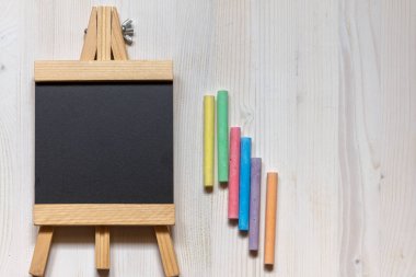 Beyaz arka plan ve renkli tebeşir üzerinde şüskül şeklinde boş bir tahta havadan görünümü