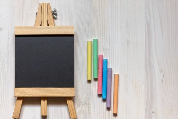 Beyaz arka plan ve renkli tebeşir üzerinde şüskül şeklinde boş bir tahta havadan görünümü