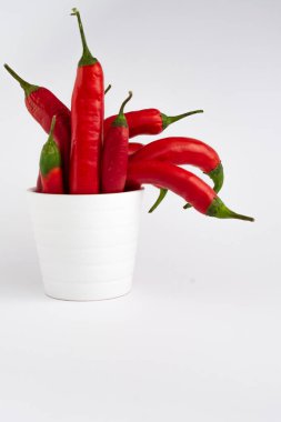 Beyaz arka planda beyaz kasedeki biberlerin görüntüsü ve dikey olarak kopya alanı