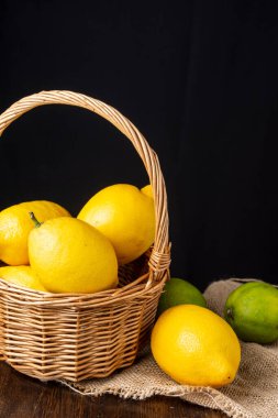 Limonlu sepetin yakın çekimi, limonlu çuval bezi, tahta masa, siyah arka plan, dikey