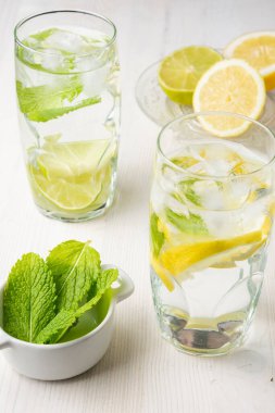 Limonlu ve limonlu iki bardak suyun üst görüntüsü yarım limon ve naneli, dikey.