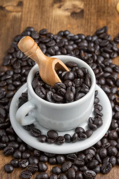 ローストコーヒー豆とスプーン付きの白いコーヒーカップの空中ビュー 木製のテーブルの上 選択的フォーカス — ストック写真