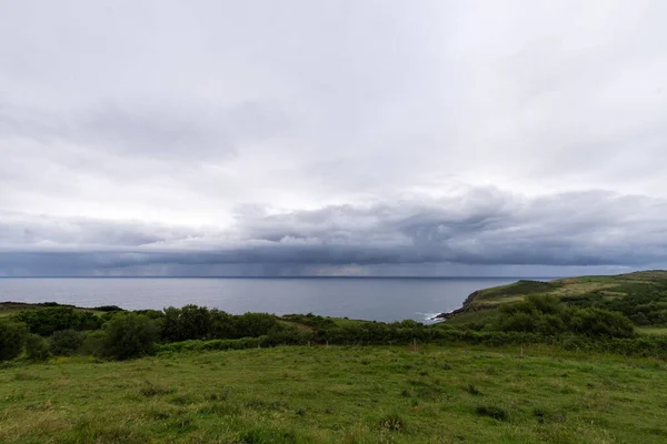 背景に海と緑のフィールドのビュー 曇り空の夏の午後 スペイン北部 水平方向 — ストック写真