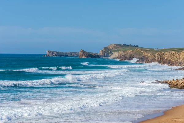 Güneşli bir yaz öğleden sonrasında İspanya, Cantabria 'da dalgalarla birlikte Liencres sahilinin yatay görüntüsü.