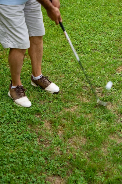 白いボールを打つゴルフシューズを持つ男のショートパンツと足のビュー 緑の芝生の上 肖像画で コピースペースと — ストック写真