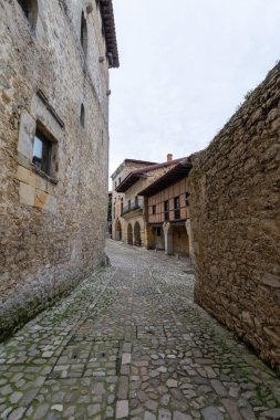Santillana del Mar, İspanya 'da 1 Ekim 2020' de taştan duvarlar arasındaki dar ortaçağ kaldırımlı caddenin dikey görüntüsü