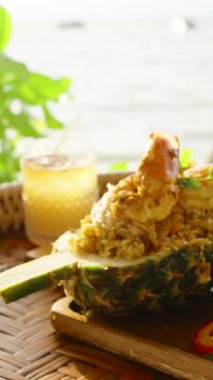 Dikey video. Karides kızartmalı pilav ve limonata bardağının yanında dokuma tepsisi, geniş açı, egzotik ada mutfağı.