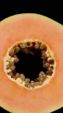 Dikey video. Papaya 'nın Yeşil Derili Turuncu Et ve Siyah Arkaplan Karşıtı Siyah Tohumlar, Taze Meyve Teftişi Konsepti