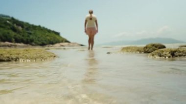 Yeşil Tepeler ve Mesafeli Kayalıklarla Sığ Suyun Üzerinde Yürüyen Kadın Bulanık Etki, Gevşeme Konsepti