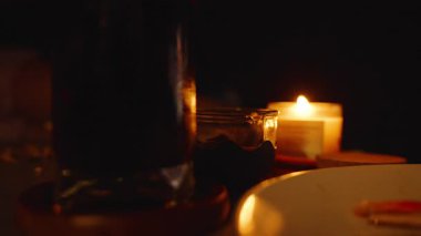 El Mum Yakınına Uzanıyor ve Loş Oda 'da Tablo Üzerine Tabaka ile Karanlık İçki Bardağı Sade TV Zaman kavramı