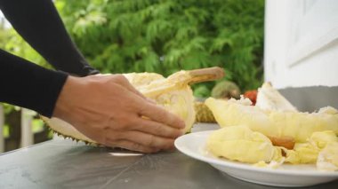 El kaldırma Taze Sarı Durian Et ve Beyaz Tabağa doğru diğer Parçalar Sağlıklı Yiyecek Konsepti Kapalı