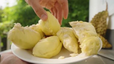Parlak Doğal Işık Sağlıklı Tropikal Gıda Konsepti ile dolu Beyaz Tabak 'tan Bir Sarı Durian Bölümü Alınıyor