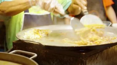 Sokak satıcılarının elleri büyük sıcak tavada makarna ile şehriye karıştırırken Tayland 'daki kalabalık markette buharlı Pad Thai pişiriyorlar.
