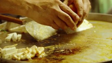 Tedarikçi ellerinin sıcak tavaya yumurta kırarak Pad Thai 'yi tofu parçaları ve buharla hazırlamak için Tayland' ın canlı pazarında görülebilen sokak yiyecekleri kavramını kapatması.