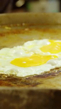 Dikey video. Tofu ve diğer malzemelerle büyük sıcak tavada kızaran yumurtaları yakın. Tayland sokak pazarında Pad Thai pişirirken.