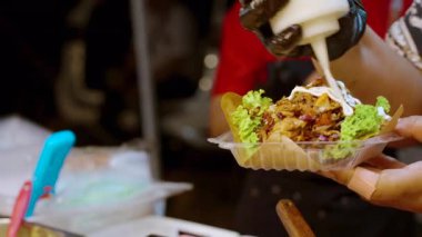 Tedarikçinin kapısına git ve tako üzerine mayonez sosu ekle. Plastik tepside et ve marul karışımı. Yemek standında müşterilere servis yaparken.