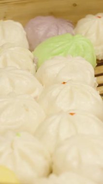 Dikey video. Bambu buharlı buharlı çöreklerin geniş açısı yumuşak desenli ve farklı dolgulu geleneksel Asya sokak yemeği kavramı.