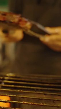 Dikey video. Izgara kaburgaların yakın çekim yeri sıcak ızgaranın altında parlak közler, sığ odak, sokak yiyecekleri kavramı