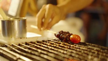 Elle ızgara et şişi ve domatesle metal sos kabının yanındaki ızgaranın üzerine sığ bir alan derinliği, sokak yemekleri konsepti.