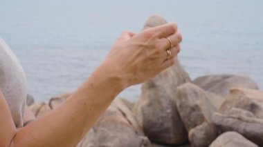 Yüzük Giyen Kadın Yüzükleri Samui Adası 'nda Deniz kenarındaki Iconic Hin Ta Hin Yai Kaya oluşumlarını işaret ediyor.