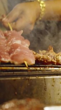 Dikey video. Slow Motion Tedarikçisi Gece Marketinde Yanan Duman Izgarası 'nda Domuz Şişi Döndürüyor, Yakın açı, Sokak Gıda Konsepti